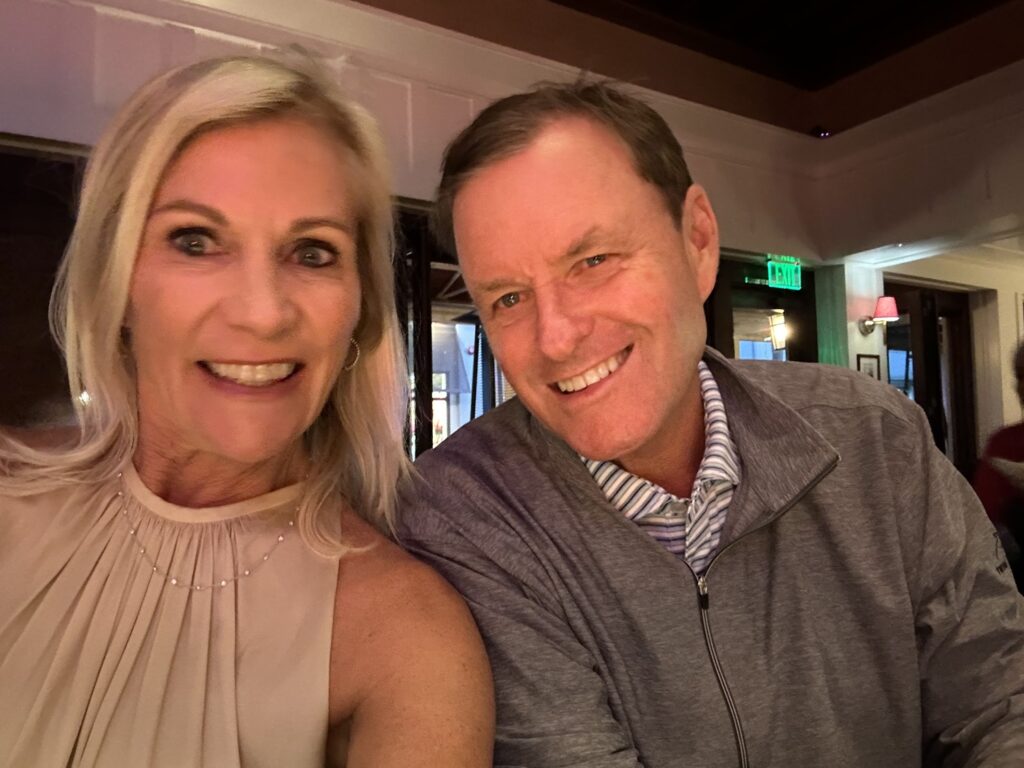 Devin Doyle and his wife smiling together during an evening dinner at a restaurant.