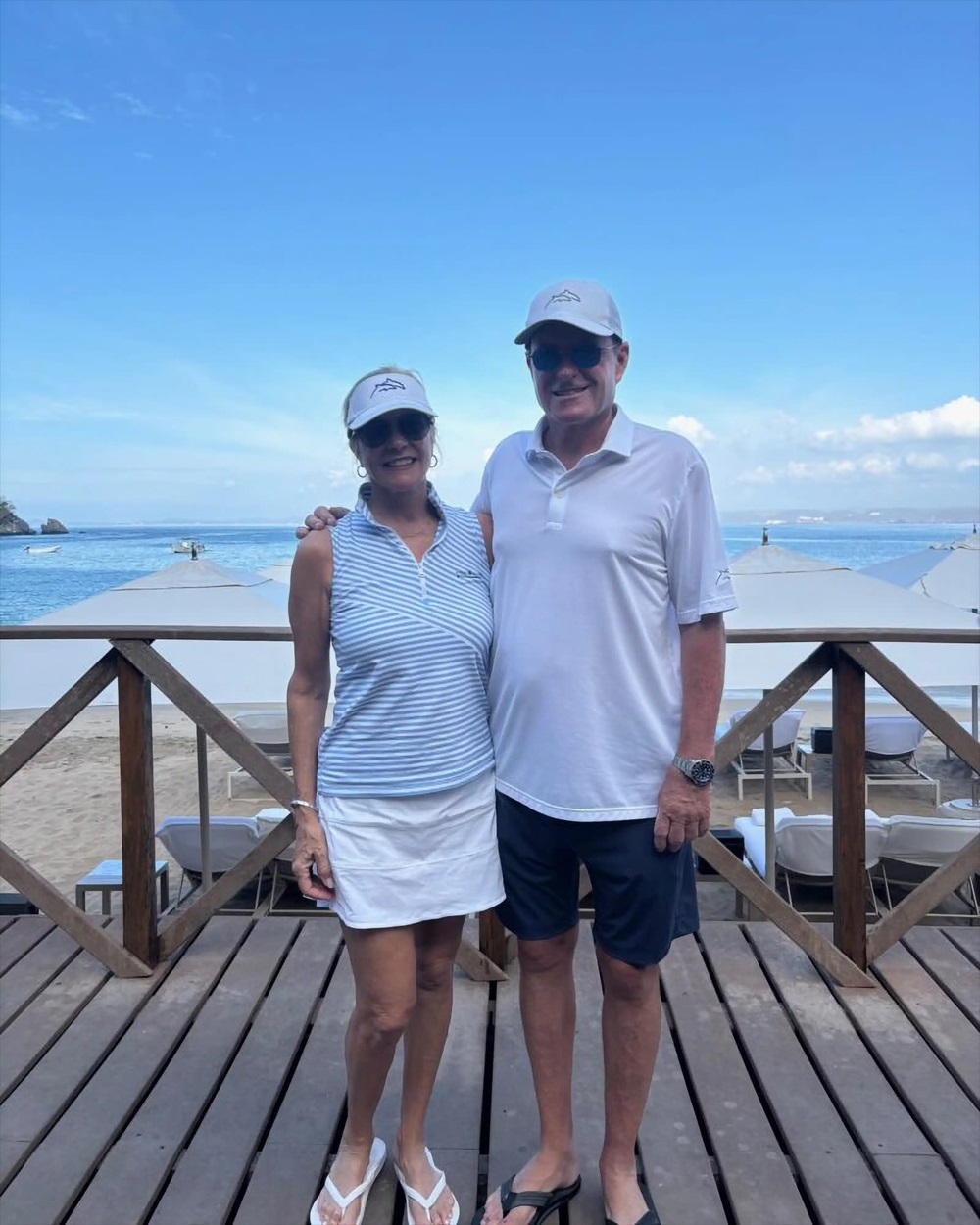 Devin Doyle and his wife posing together on a beachfront deck overlooking the ocean.